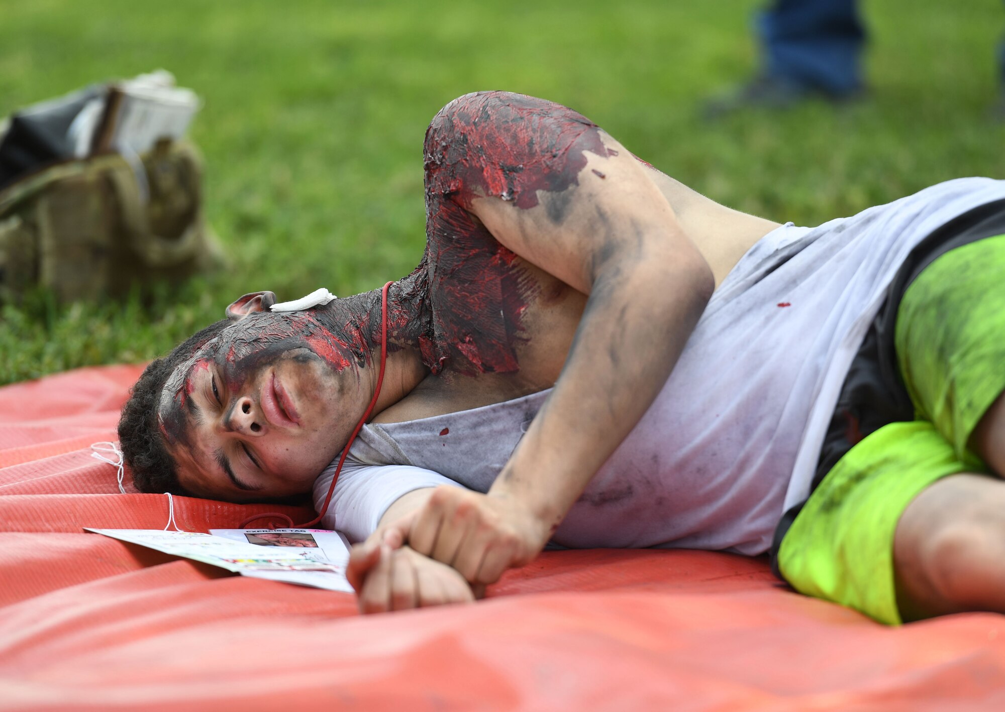 U.S. Air Force Airman 1st Class Kristian Hutchins, 334th Training Squadron student, portrays a victim lying on a triage mat awaiting medical care during a Chemical, Biological, Radiological, Nuclear exercise at Keesler Air Force Base, Mississippi, Aug. 6, 2021. The Ready Eagle exercise tested the base's ability to respond to and recover from a mass casualty event. (U.S. Air Force photo by Kemberly Groue)