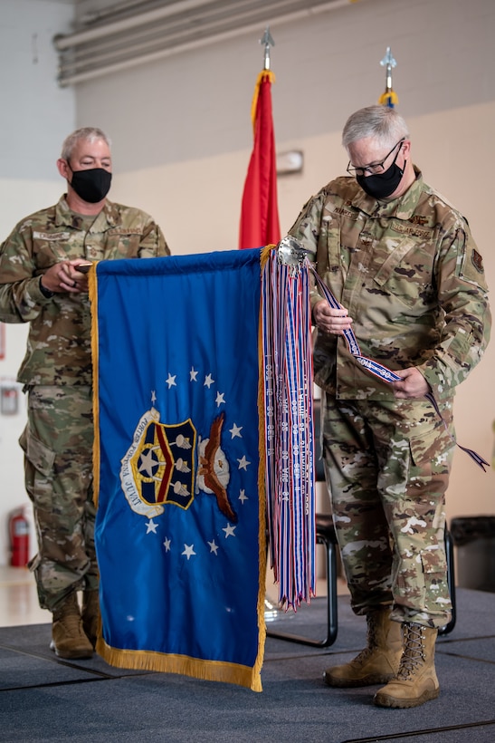 Col. David Mounkes (right), outgoing commander of the 123rd Airlift Wing, pins a streamer representing the wing’s 19th Air Force Outstanding Unit Award to the wing guidon during a ceremony at the Kentucky Air National Guard Base in Louisville, Ky., Aug. 7, 2021. The award, which is bestowed on the top 10 percent of all units, recognizes the wing’s outstanding achievement across a full spectrum of operations, from homeland disaster response to the war effort overseas, between October 2017 and September 2019. No other airlift unit in the United States Air Force — active duty, Guard or Reserve — has earned 19 AFOUAs. (U.S. Air National Guard photo by Dale Greer)