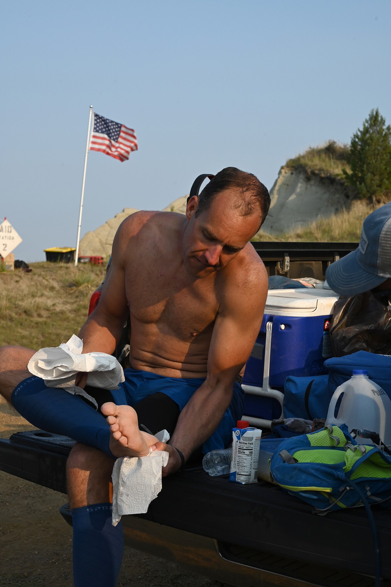 Senior Master Sgt. Brandon Miller looks at his bare foot as he rests at a checkpoint location on the Maah Daah Hey Trail 107.3-mile ultramarathon running race in the North Dakota badlands July, 31, 2021.