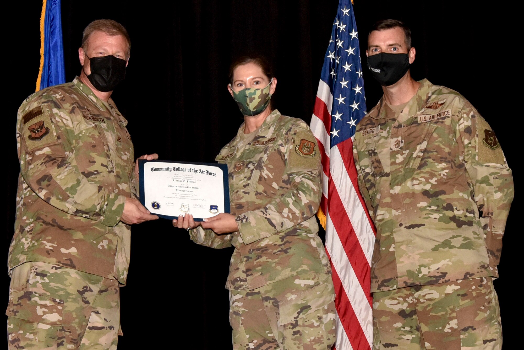 (center) Tech. Sgt. Lindsay Jeffries, 73rd Aerial Port Squdron, receives their Community College of the Air Force degree from (left) Col. Allen Duckworth, 301 FW commander, and (right) Chief Master Sgt. Michael Senigo, 301 FW command chief, during a graduation ceremony at U.S. Naval Air Station Joint Reserve Base Fort Worth, Texas, August 7, 2021. The CCAF degree is awarded to Airmen who have completed the requirements for an Associate of Applied Science Degree. (U.S. Air Force photo by Staff Sgt. Randall Moose)