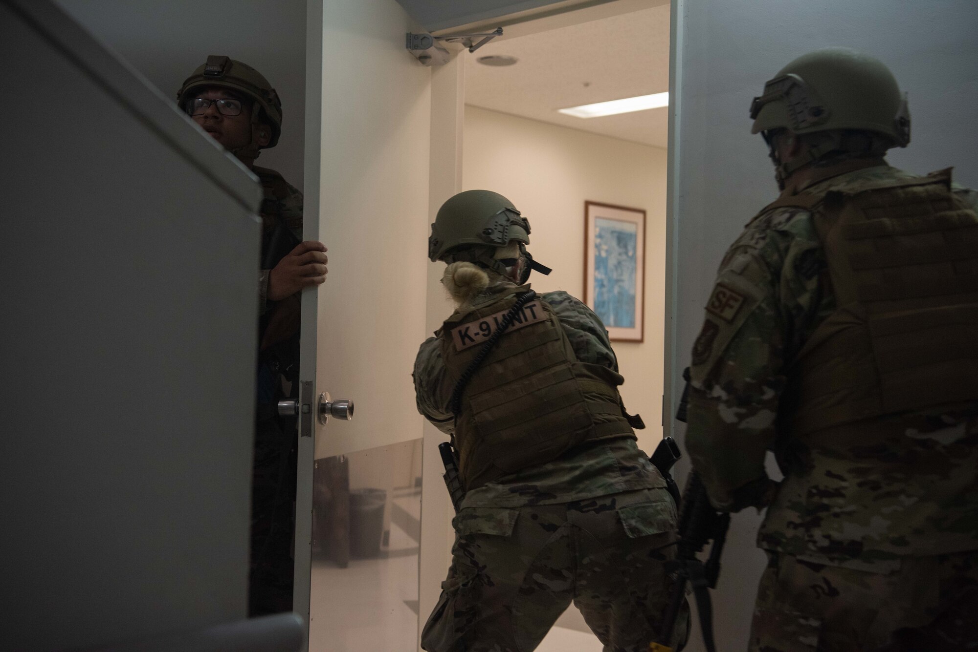 Security Forces members secure a hallway and enter a room.
