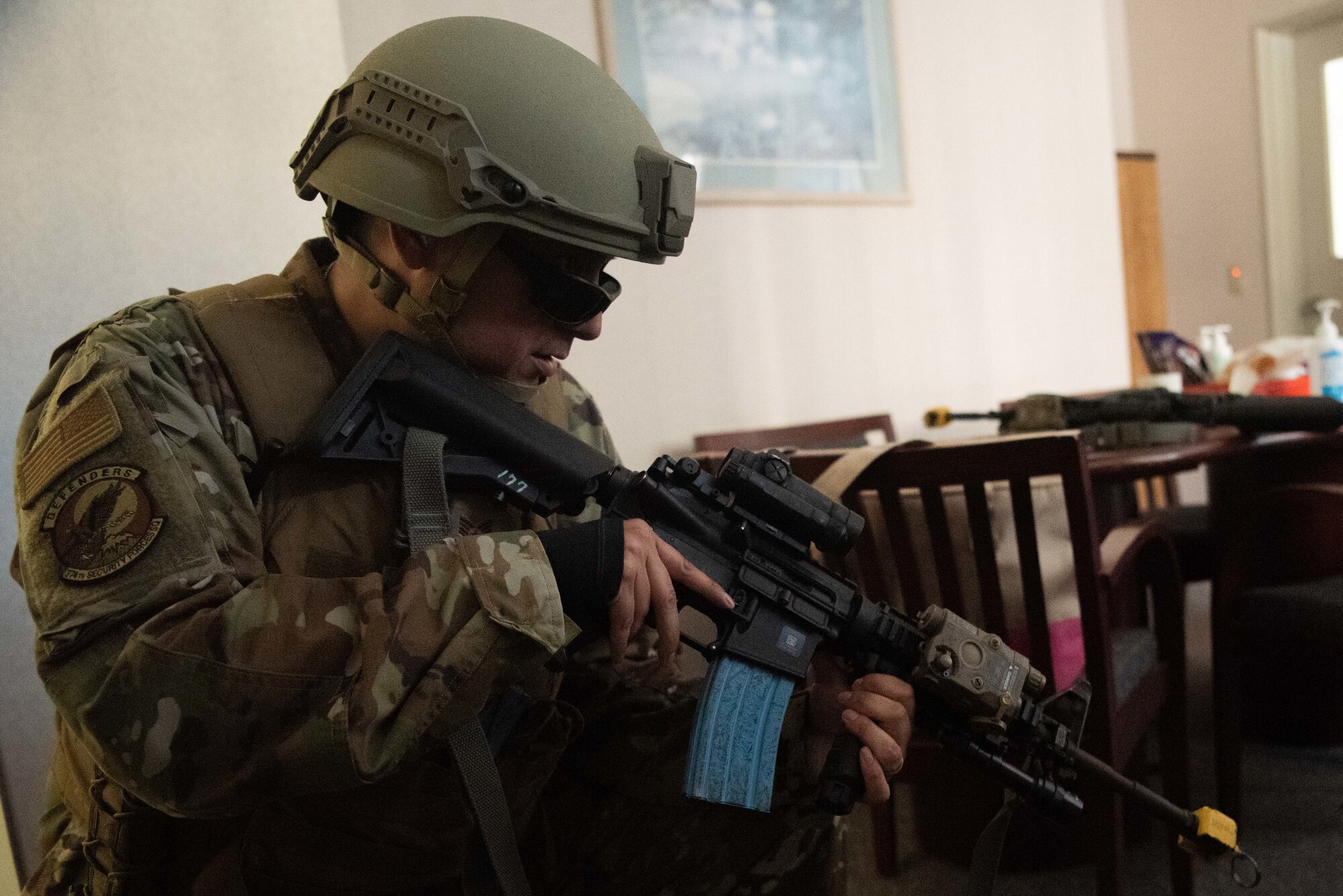 Security Forces member kneels holding a weapon.