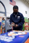 JOINT BASE ELMENDORF-RICHARDSON, Alaska -- Dwight Brown, Anchorage Area Commissary store manager, rings up a customer's cart during a Commissary sale Aug. 7, 2021, at the Alaska Army National Guard Aviation Facility, Bethel, Alaska. An Alaska Air National Guard C-17 Globemaster III moved tons of groceries and supplies from Joint Base Elmendorf-Richardson to Bethel to offer the goods to eligible residents at discount prices. (U.S. Air National Guard photo by David Bedard/Released)