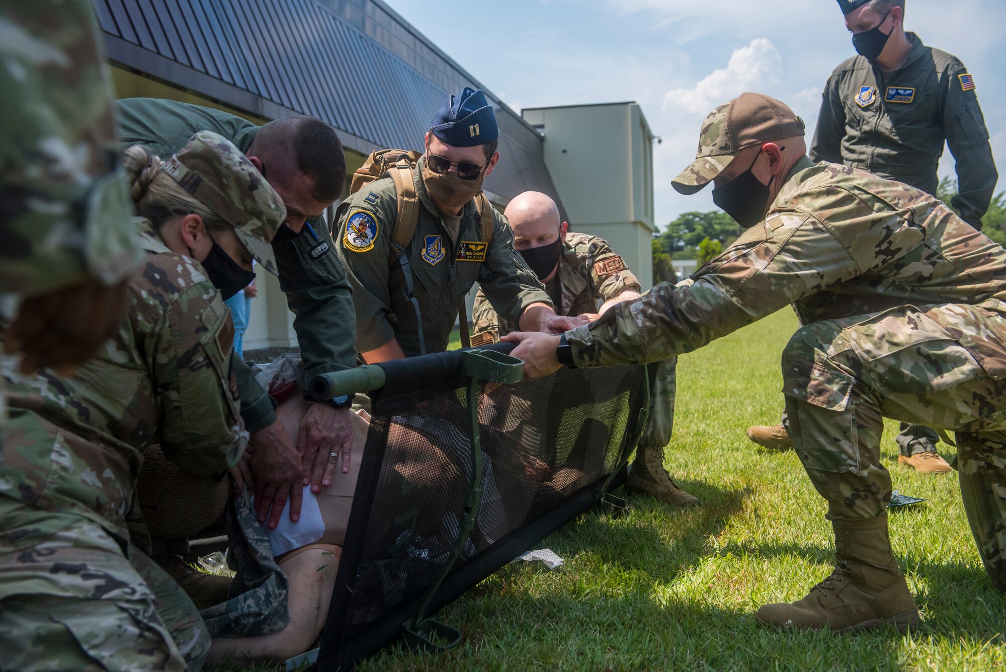 Group of servicemembers apply medical aid to a simulated patient.