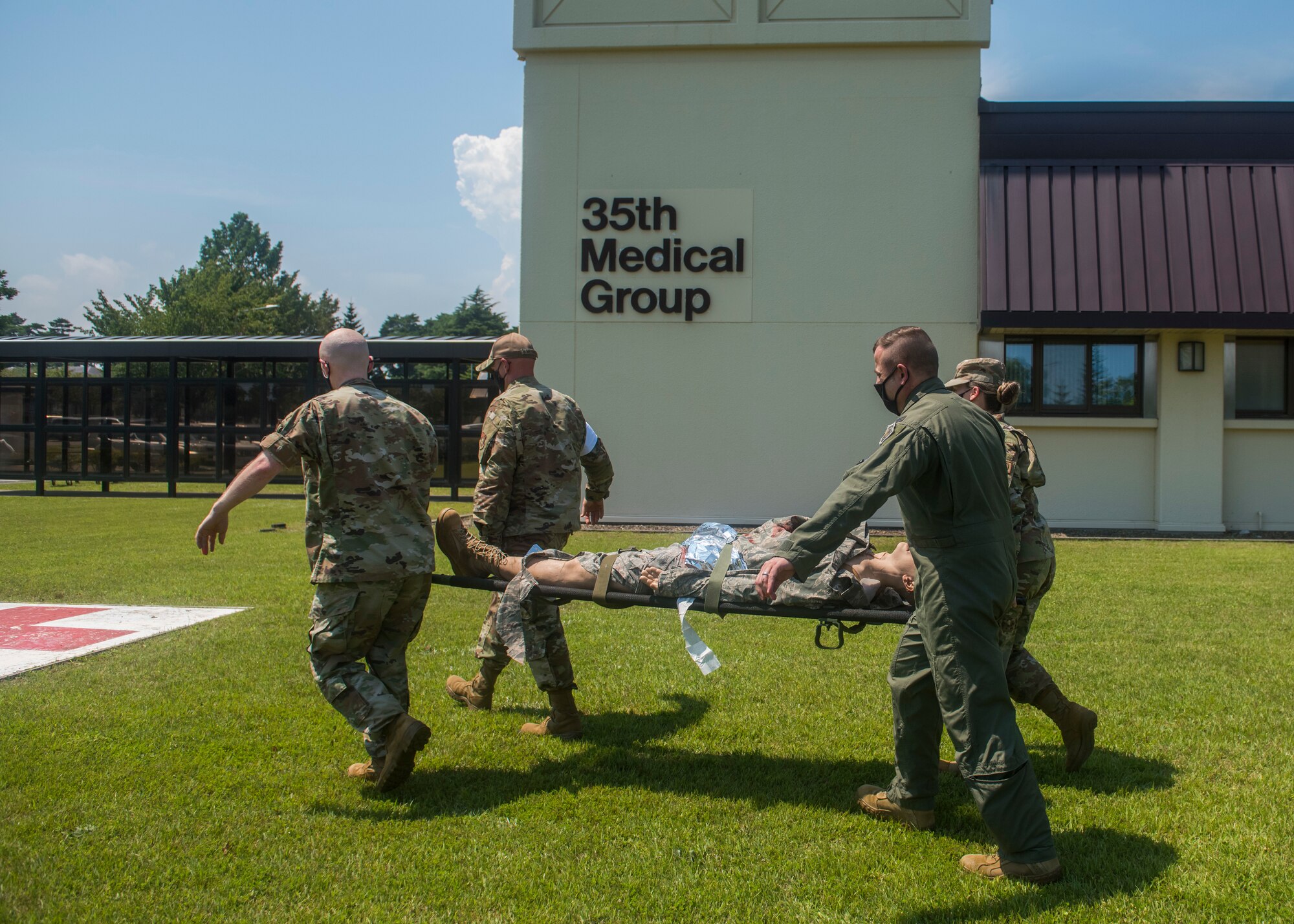Four servicemembers in uniform, carry a simulated patient on a stretcher.