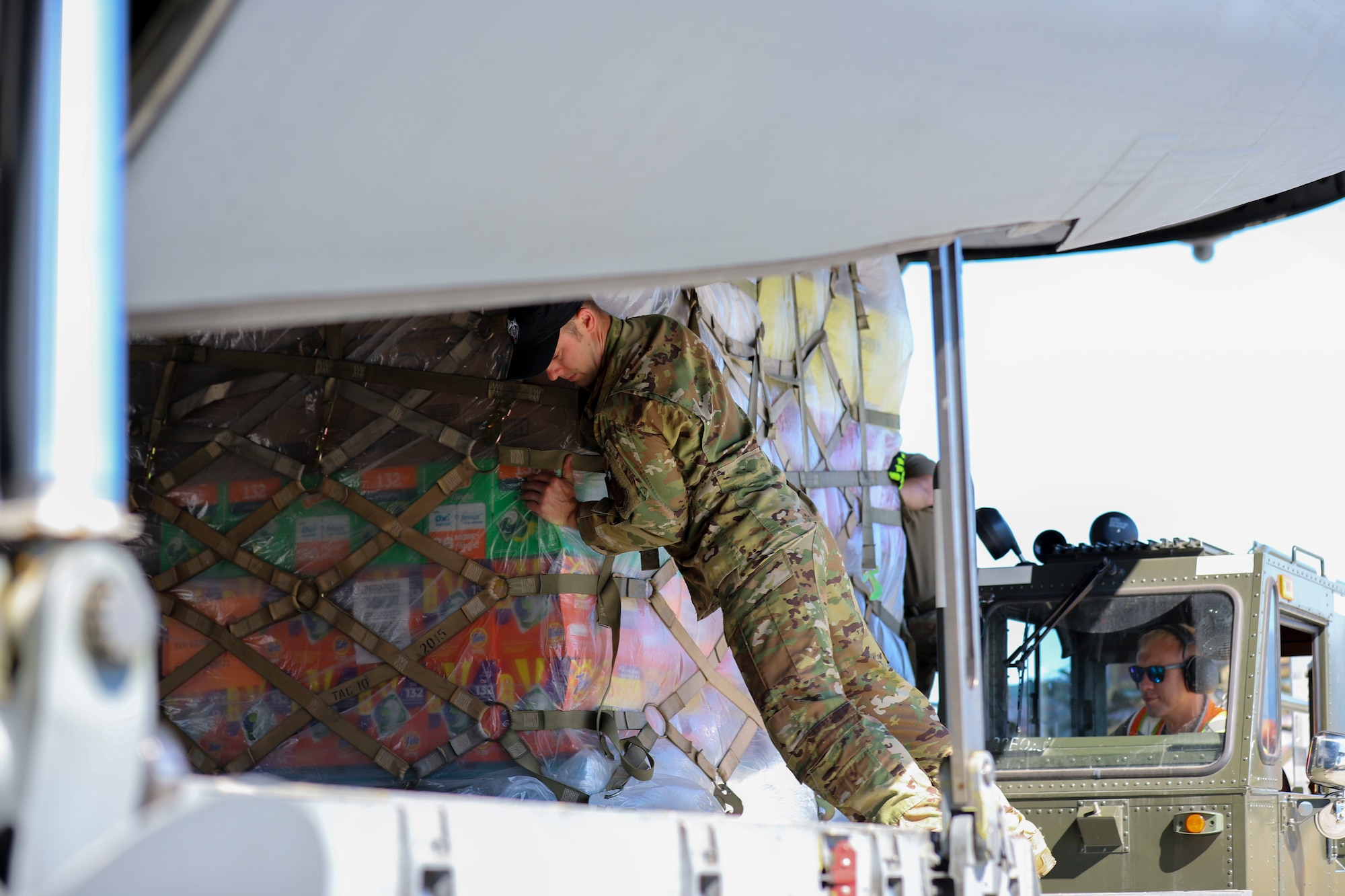 JOINT BASE ELMENDORF-RICHARDSON, Alaska -- Alaska Air National Guard Senior Master Sgt. Tristan Maxwell, 144th Airlift Squadron loadmaster, and Staff Sgt. Brock Shope (driving), 176th Logistics Readiness Squadron transportation craftsman, load cargo for the Defense Commissary Agency from Joint Base Elmendorf-Richardson via a C-17 Globemaster III aircraft from the 176th Wing’s 144th Airlift Squadron to the remote village hub of Bethel, Alaska, Aug. 2, 2021. The AKNG partnered with DeCA in order to provide discounted groceries to eligible military- and DoD-affiliated patrons during a one-day event Aug. 7. (U.S. Army National Guard photos by 1st Lt. Balinda O’Neal Dresel)