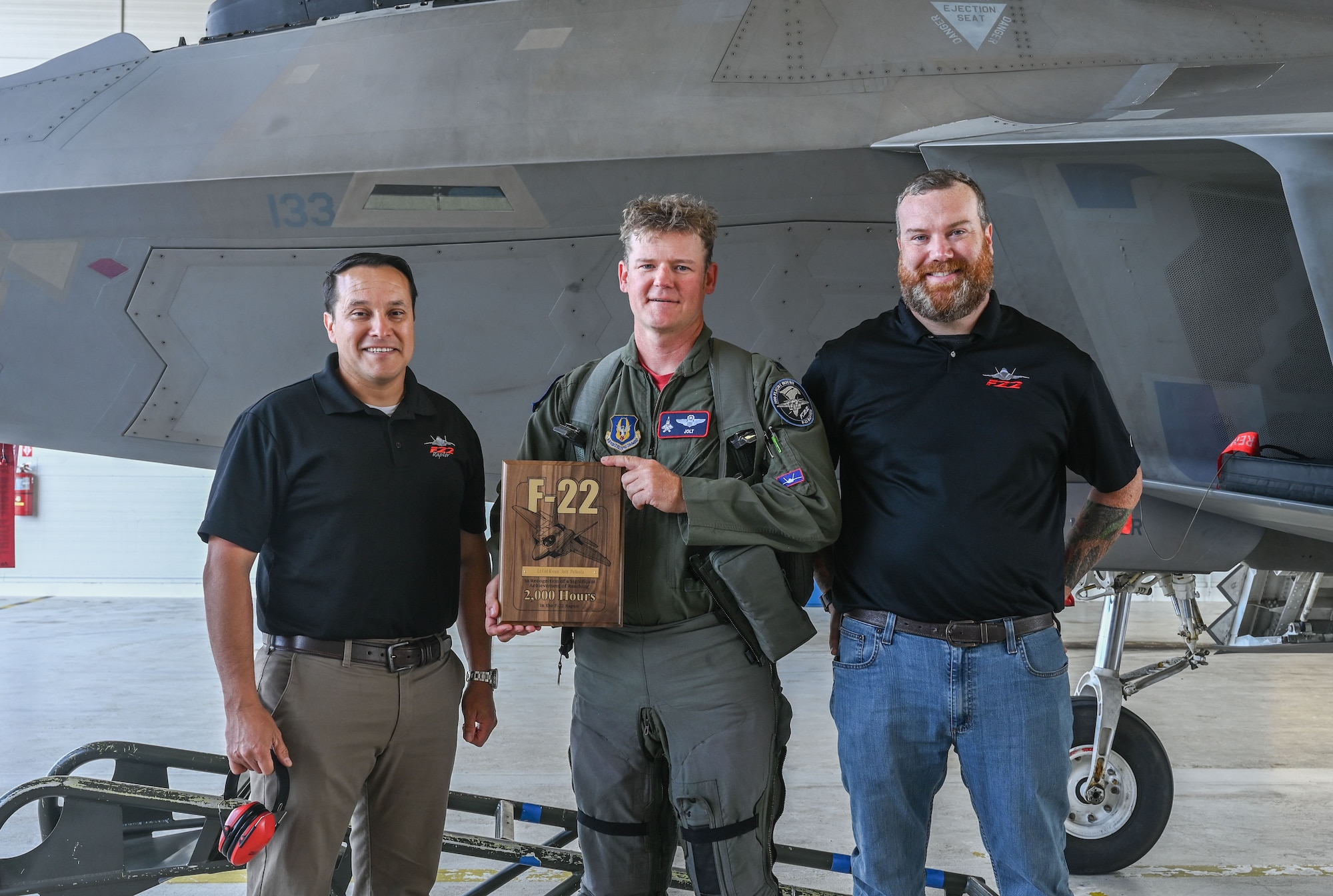 Eli Clark and Victor Sanchez Jr. present Lt. Col. Ryan Pelkola with a plaque recognizing his 2,000 flight hours accomplishment.