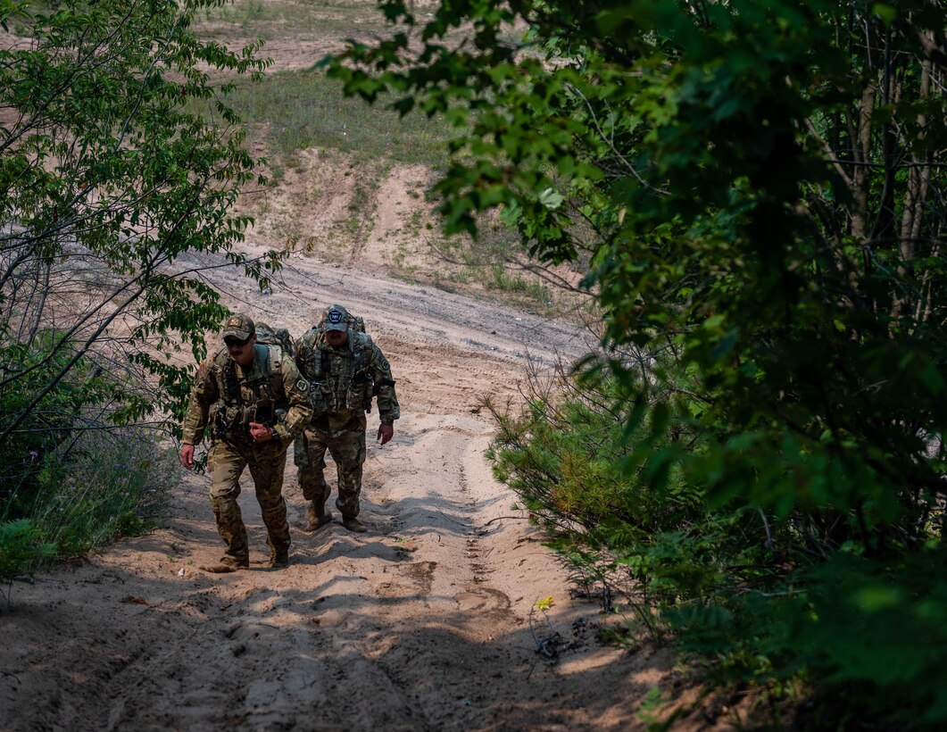 U.S. Army Staff Sgt. Wyatt Brown, left, 2-211th Army Regiment flight medic, and Sgt. Brandin Frey, 2-211th Army Regiment aircraft mechanic, walks up a hill in a simulated Combat Search and Rescue mission during Northern Strike (NS) 21-2 near Ontonagon, Michigan, Aug. 3, 2021. NS maximizes combat readiness by providing adaptable, cost effective training ranging from individualized tactical skills to near-peer contested threat and combined arms environments focused on joint and coalition force integration and domain convergence. (U.S. Air National Guard photo by Senior Airman Paul Helmig)