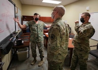 Joint Task Force Civil Support (JTF-CS) J3 Operations Director Marine Lt. Col. Christopher Grasso discusses subordinate unit task organization with Army Capt. Darren Hamby and Air Force Maj. William Matthews during exercise Vibrant Response 21.2.