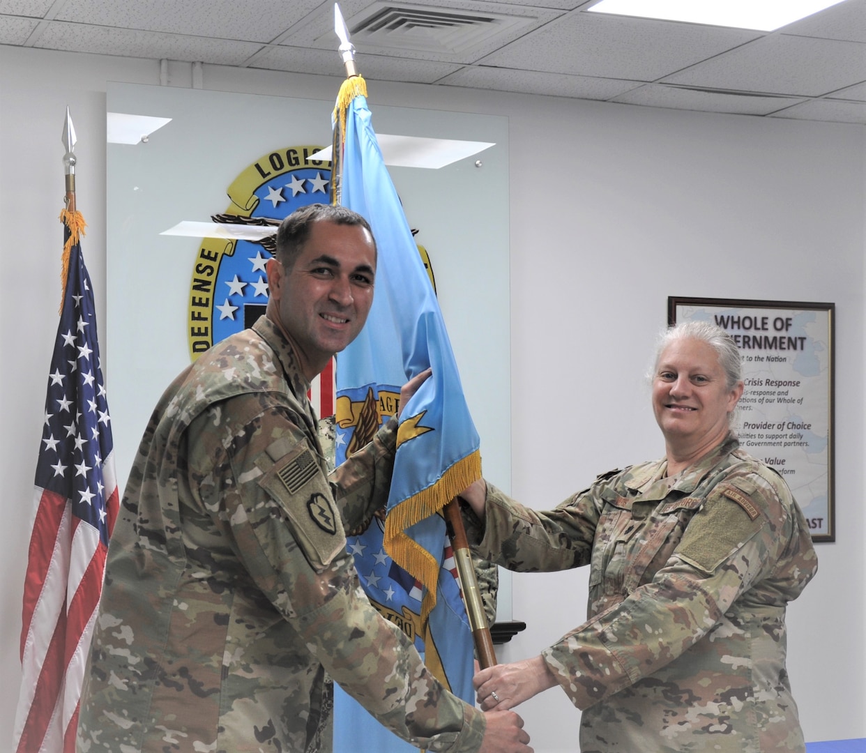 two military officers pass a flag