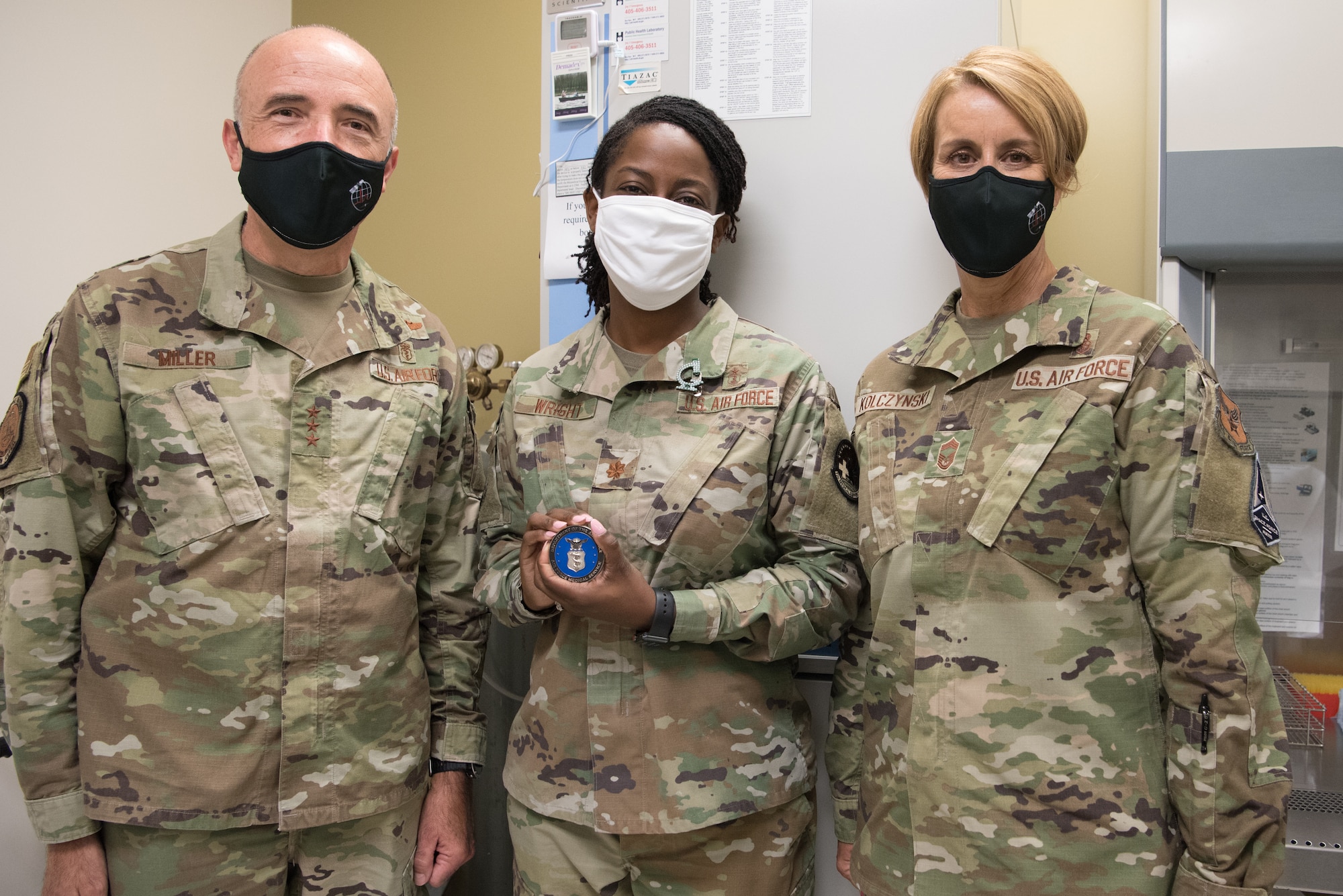 Three Airmen in group photo, middle Airman holding coin