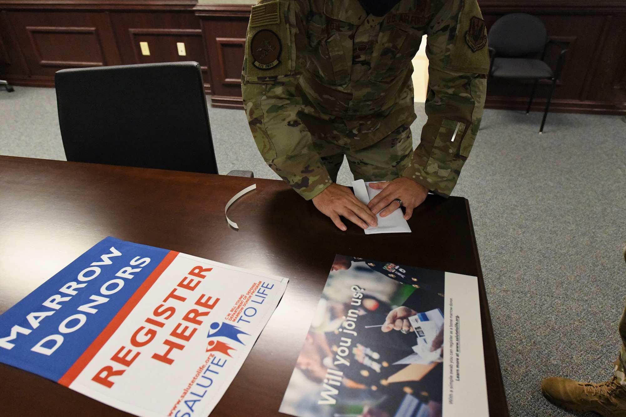 A uniformed member seals an envelope on a table.