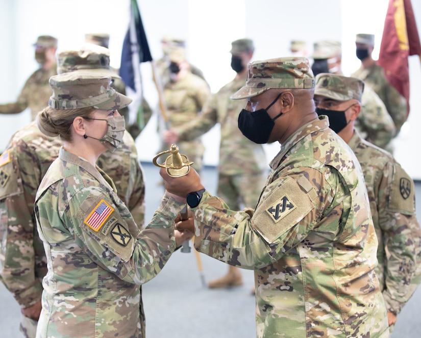 Command Sgt. Maj. Ciearro M. Faulk, outgoing senior enlisted advisor for the 143d Sustainment Command (Expeditionary), passes the NCO sword to Brig. Gen. Pamela L. McGaha, commanding general of the 143d ESC, during the command's Change of Responsibility ceremony held at its headquarters in Orlando, Fla.