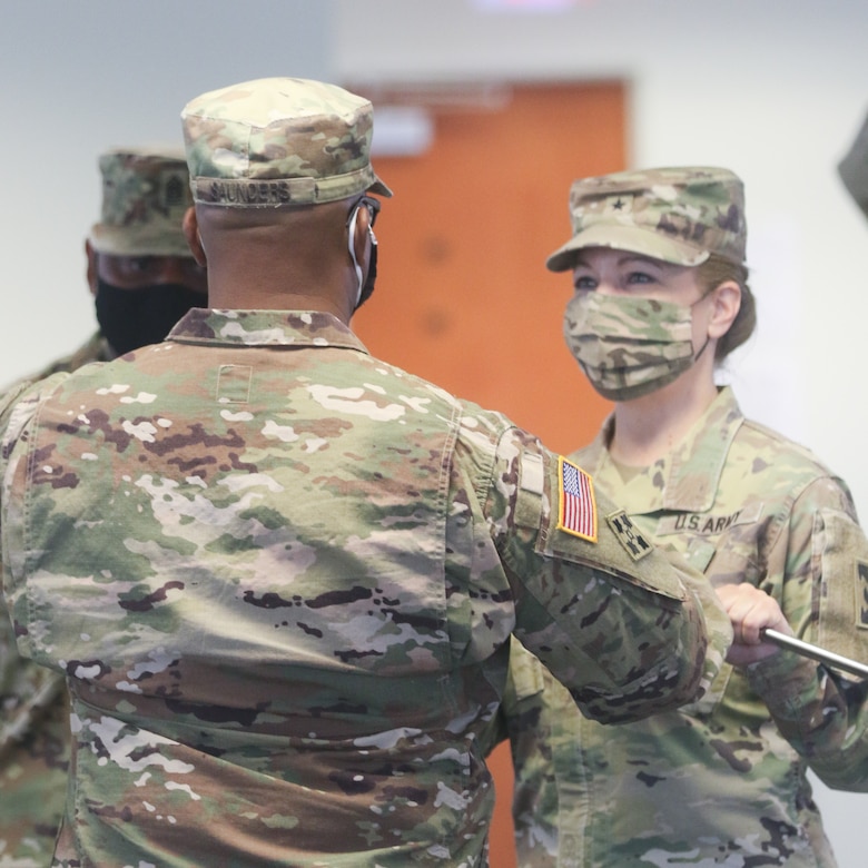 Brig. Gen. Pamela L. McGaha, commanding general of the 143d Sustainment Command (Expeditionary), passes the NCO sword to Command Sgt. Maj. Ricardo M. Saunders, the command's new senior enlisted advisor, during the command's Change of Responsibility ceremony held at its headquarters in Orlando, Fla.