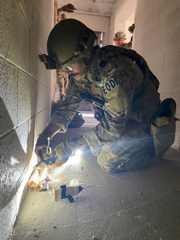 An explosives ordinance disposal technician in a US Air Force uniform, works on a simulated explosive device during a training exercise.