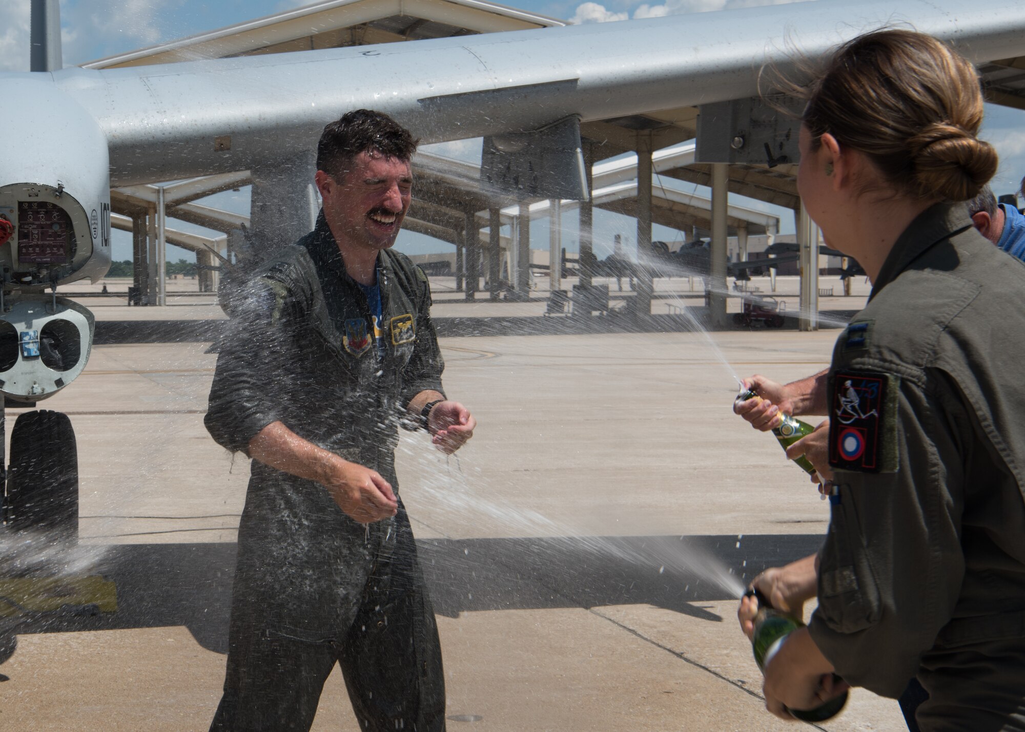 Capt. Lacey Orians sprays her husband Capt Stephen Orians with water and Champagne in front of his A-10 Thunderbolt II.