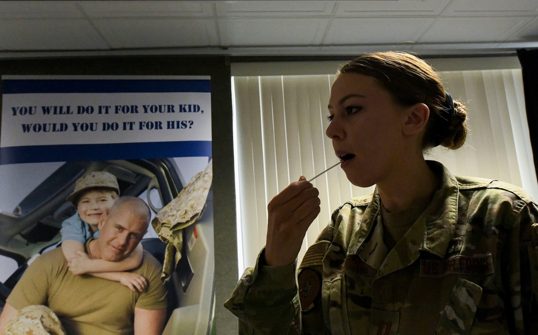 Female uniformed member swabs inner cheek for bone marrow donor registration