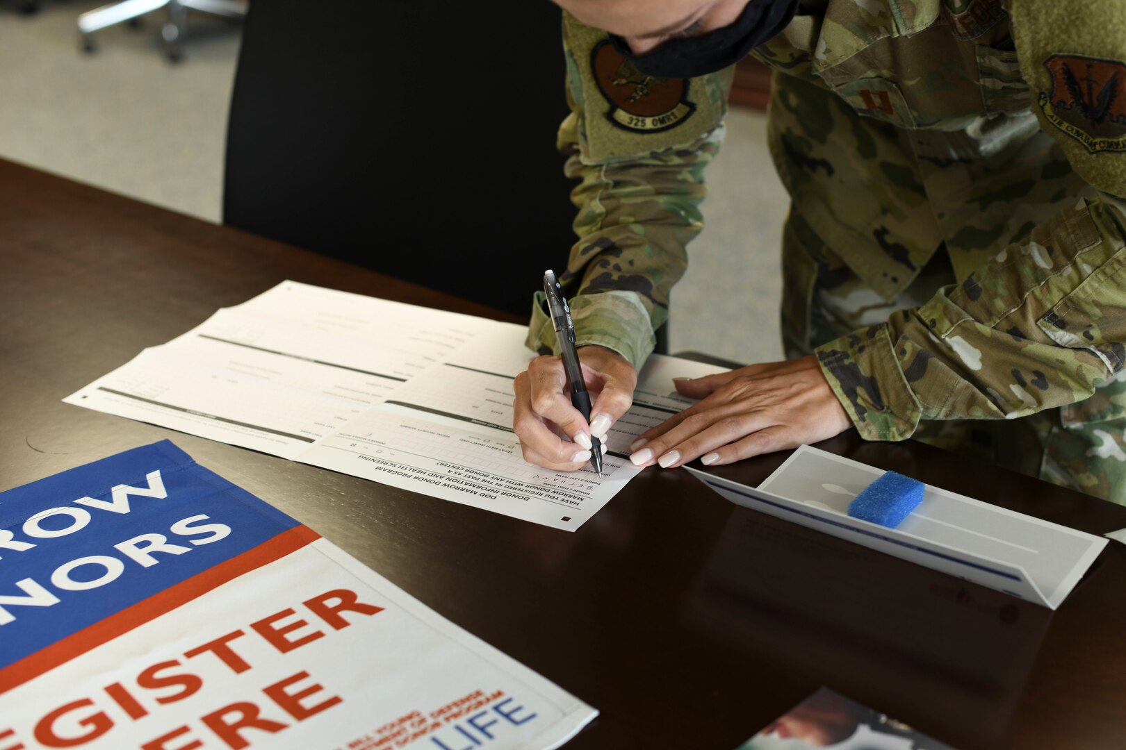 Female uniformed member fills out bone marrow donor registration forms.