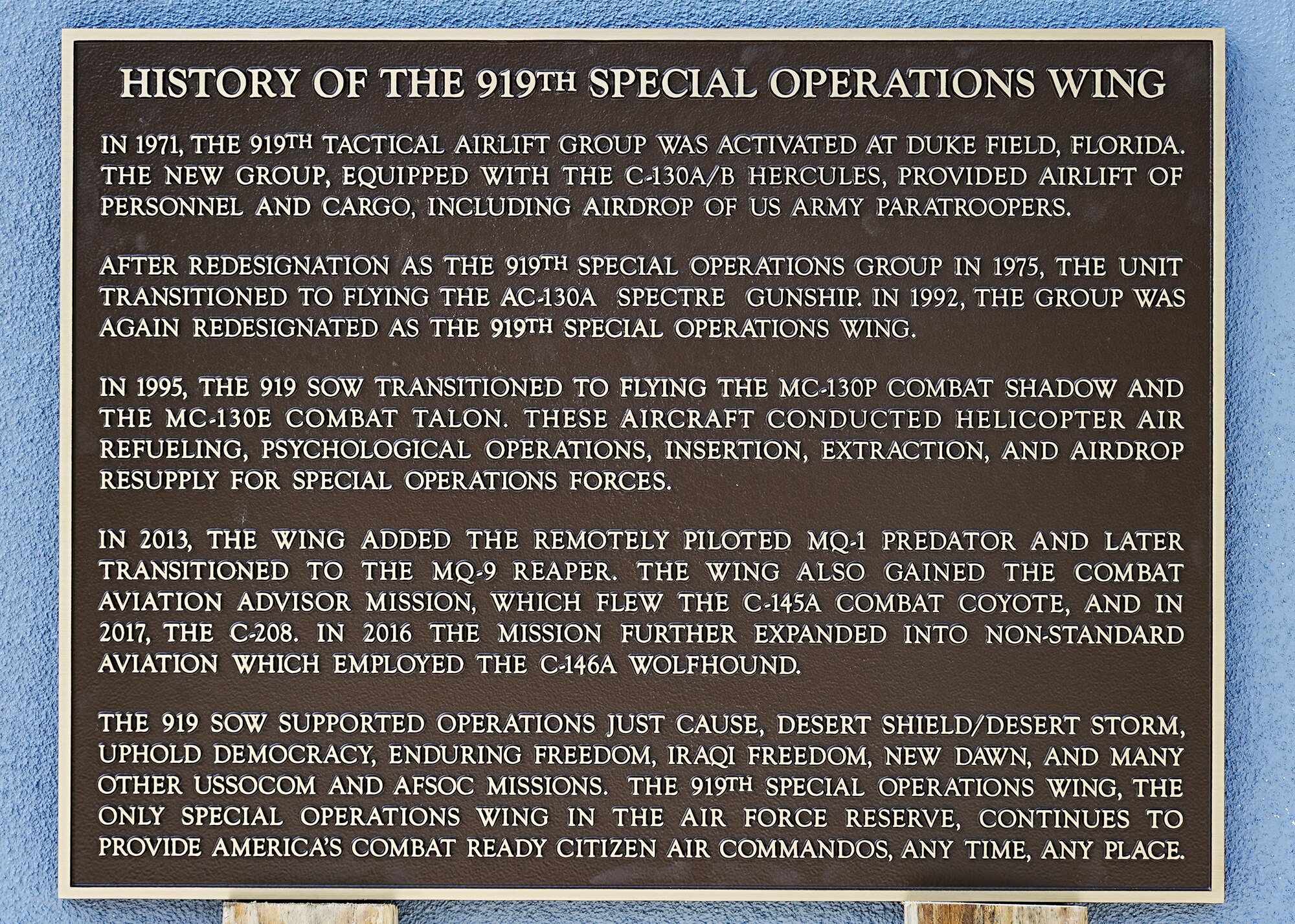 Metal plaque sits on wood planks leaned against concrete wall