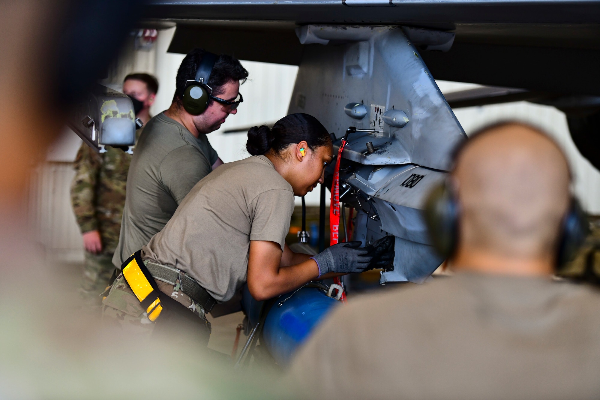 An Airman secures a bomb onto a jet.
