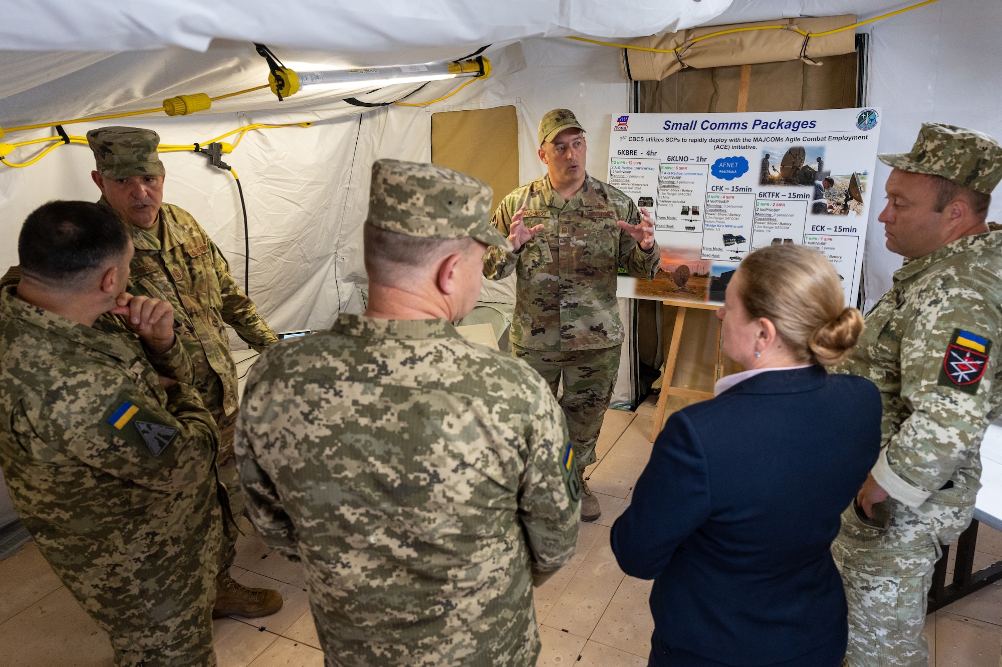 Service members standing next to a capabilities display in a tent.