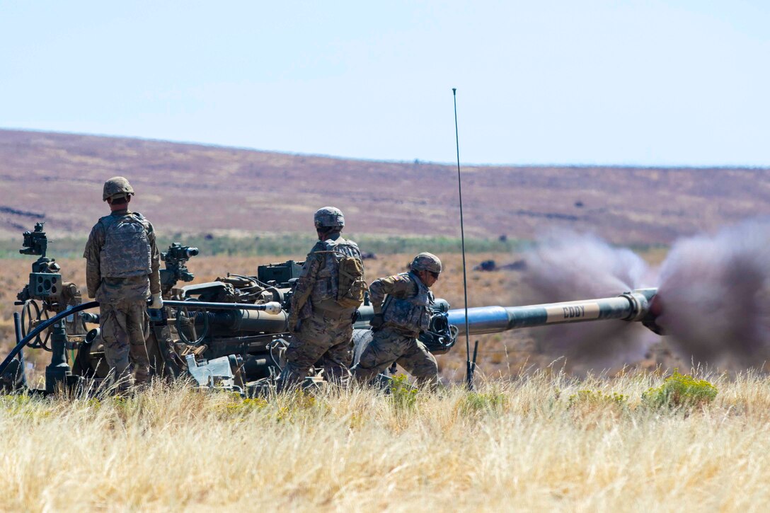 Soldiers fire a howitzer.
