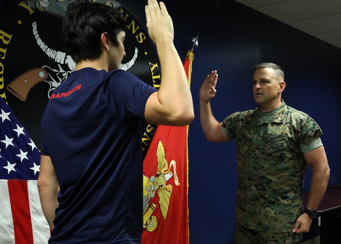 Daniel Hayek (left) takes his Oath of Enlistment from his father, Maj. Richard Hayek, the Commanding officer of Marine Corps Recruiting Station Kansas City, before signing an active duty contract with the U.S. Marine Corps at Kansas City Military Entrance Processing Station in Kansas City, Mo., July 26, 2021. By committing to the Marines, Daniel is poised to become a fourth-generation service member in his family-- following the footsteps of his mother, father, grandfather and great-grandfather. Daniel graduated from Navarre High School in Navarre, Fla., in 2020.