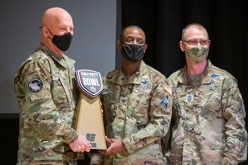Gen. John W. “Jay” Raymond, U.S. Space Force chief of space operations, and Chief Master Sgt. of the Space Force Roger A. Towberman, pose for a photo with Tech. Sgt. Maurice Moyer, team captain for the Department of the Air Force Gaming League’s Space Force Team, while he holds the Call of Duty Endowment Bowl Trophy. The Space Force team were the season one tournament winners.