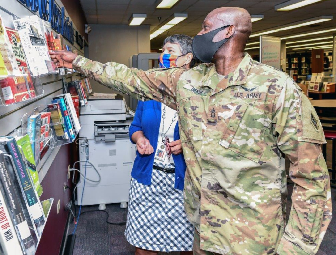 Master Sgt. Osae Bekoe with the U.S. Army Medical Test and Evaluation Activity reviews the featured titles at the MEDCoE Stimson Library with the assistance of library director Jodi Quesnell.