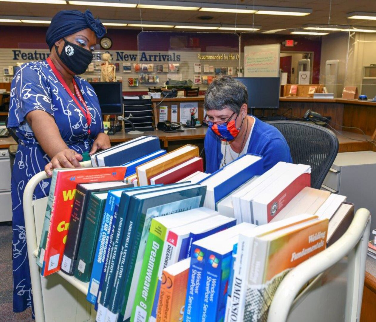 Jodi Quesnell (right), Stimson Library director, and library technician Lakeitra Spight look through a cart of books before placing them on the shelves.