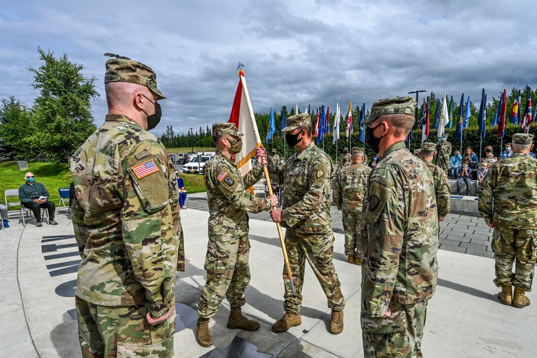 Brig. Gen. Charles “Lee” Knowles, commander of the Alaska Army National Guard, receives the unit guidon from Col. Matthew Schell, outgoing commander of the 297th Regional Support Group, during a change of command ceremony at the Lestenkof Plaza on Joint Base Elmendorf-Richardson, Alaska, Aug 7, 2021. The passing of the unit colors symbolizes the transfer of authority and commitment to the Soldiers as it is passed from Schell to the incoming commander, Col. Thomas “Alex” Elmore. (U.S. Army photo by Sgt. Heidi Kroll)
