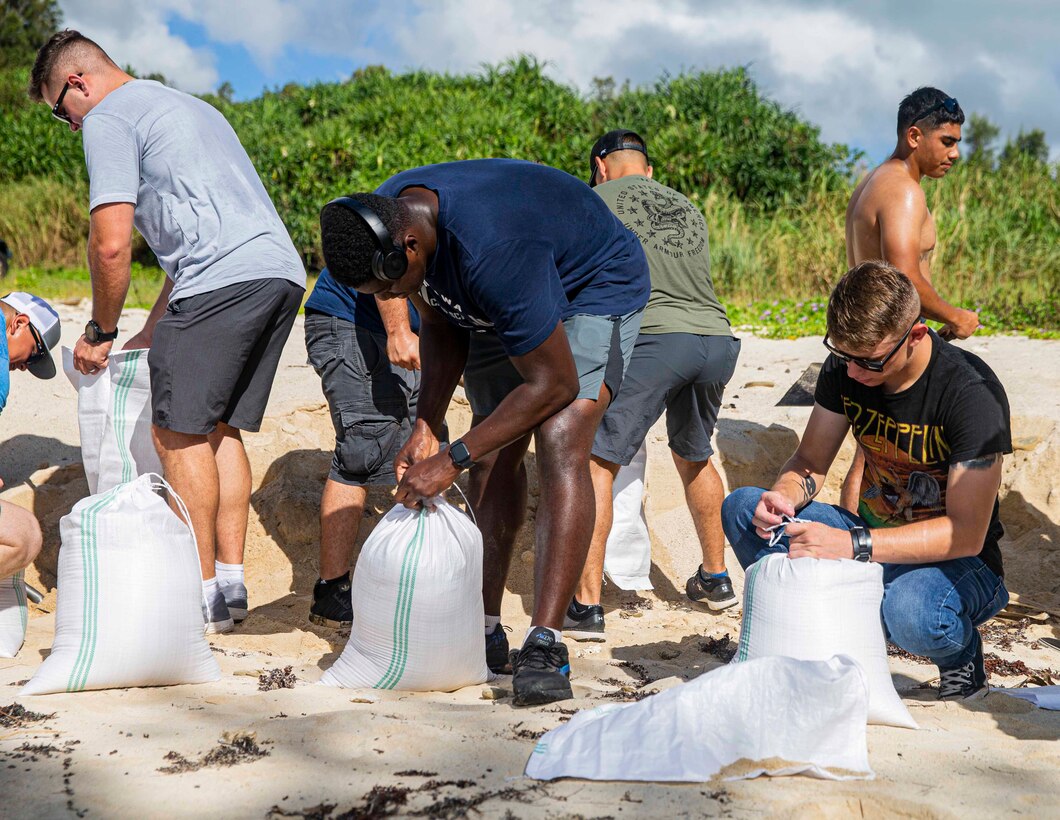 海兵隊員らが豊原地区のシーグラスビーチで、損傷した道路を補修するためのサンドバッグに砂を詰める。