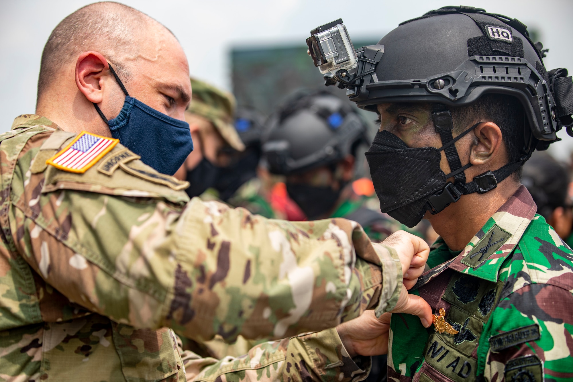 A U.S. Army soldier pins a gold pin on an Indonesian Soldier.