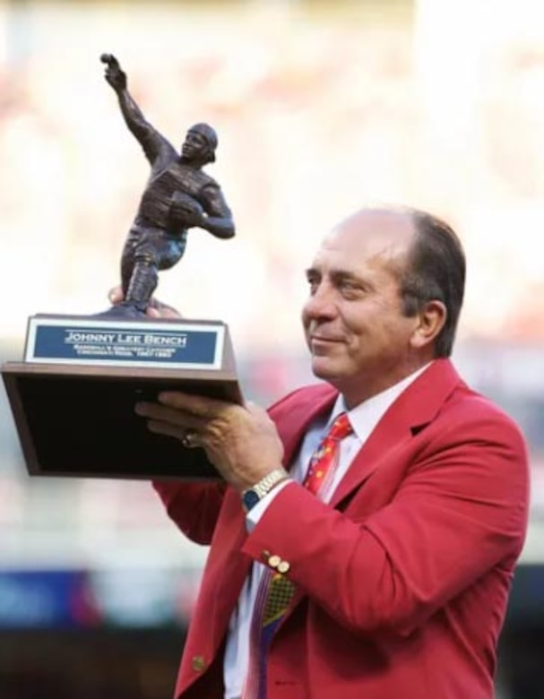 A man holds a small statue that's mounted on a wooden base.