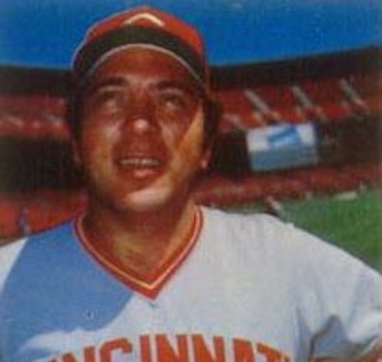 A baseball player poses for a photograph with empty bleachers behind him.