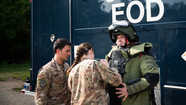 Col. Mark Dmytryszyn, 2nd Bomb Wing commander, puts on a bomb suit with the help of Airman 1st Class Paris Permenter, left, and Senior Airman Janie Roberts, middle, 2nd Civil Engineer Squadron explosive ordnance disposal technicians, at Barksdale Air Force Base, Louisiana, Aug. 9, 2021. During his visit, Dmytryszyn conducted a simulated operation involving a training improvised explosive device. (U.S. Air Force photo by Senior Airman Jacob B. Wrightsman)