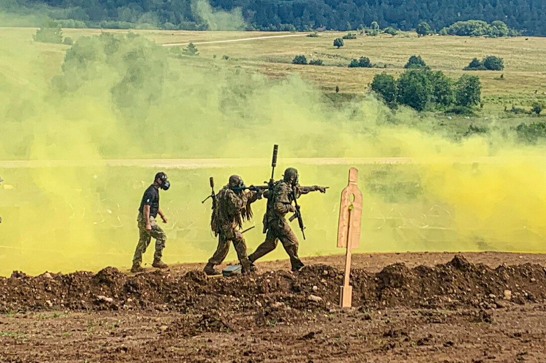 Three soldiers walk through green smoke, two hold weapons.