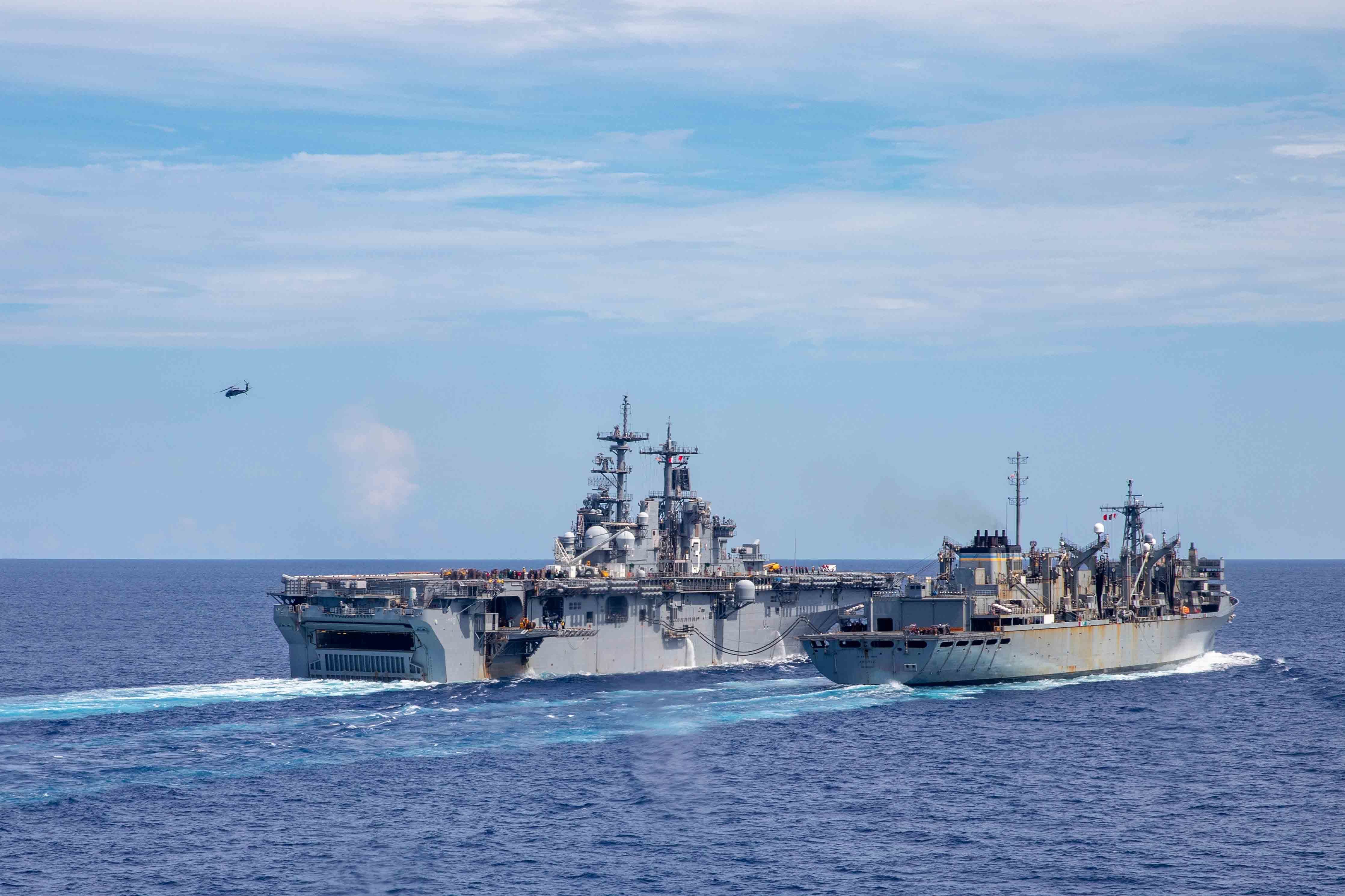 ATLANTIC OCEAN (Aug. 9, 2021) A helicopter takes off from the Wasp-class amphibious assault ship USS Kearsarge (LHD 3) to conduct vertical replenishment with Military Sealift Command fast combat support ship USNS Arctic (T-AOE 8) as Sailors participate in Large-Scale Exercise (LSE) 2021.