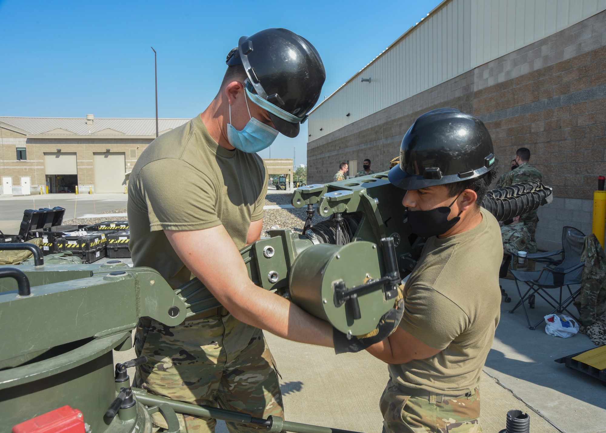 Two 726th Air Control Squadron Airmen work together to install a jack screw to the base of a Small Aperture Antenna.