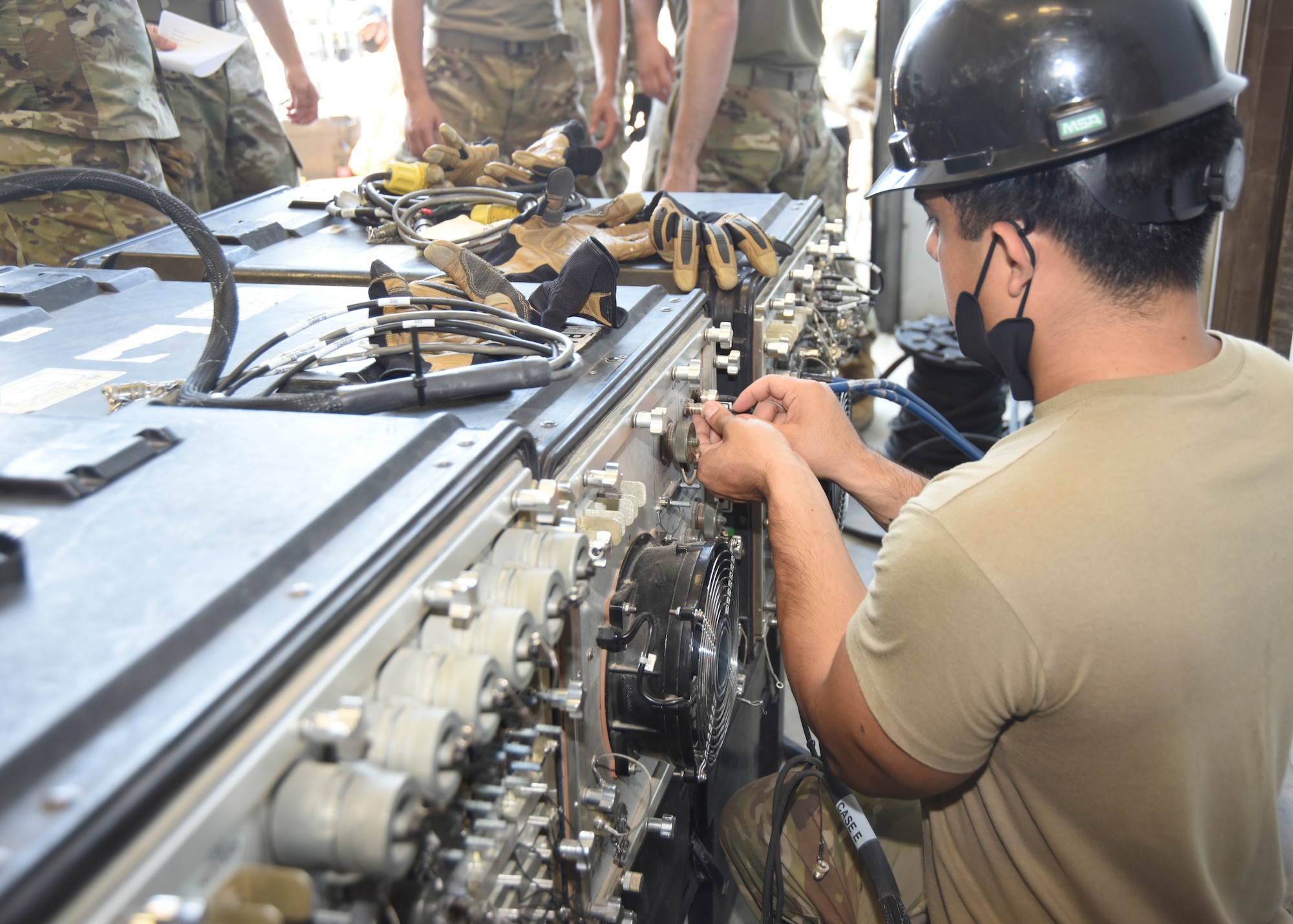 An 726th Air Control Squadron Airman plugs a cord to the back of an electronic case.