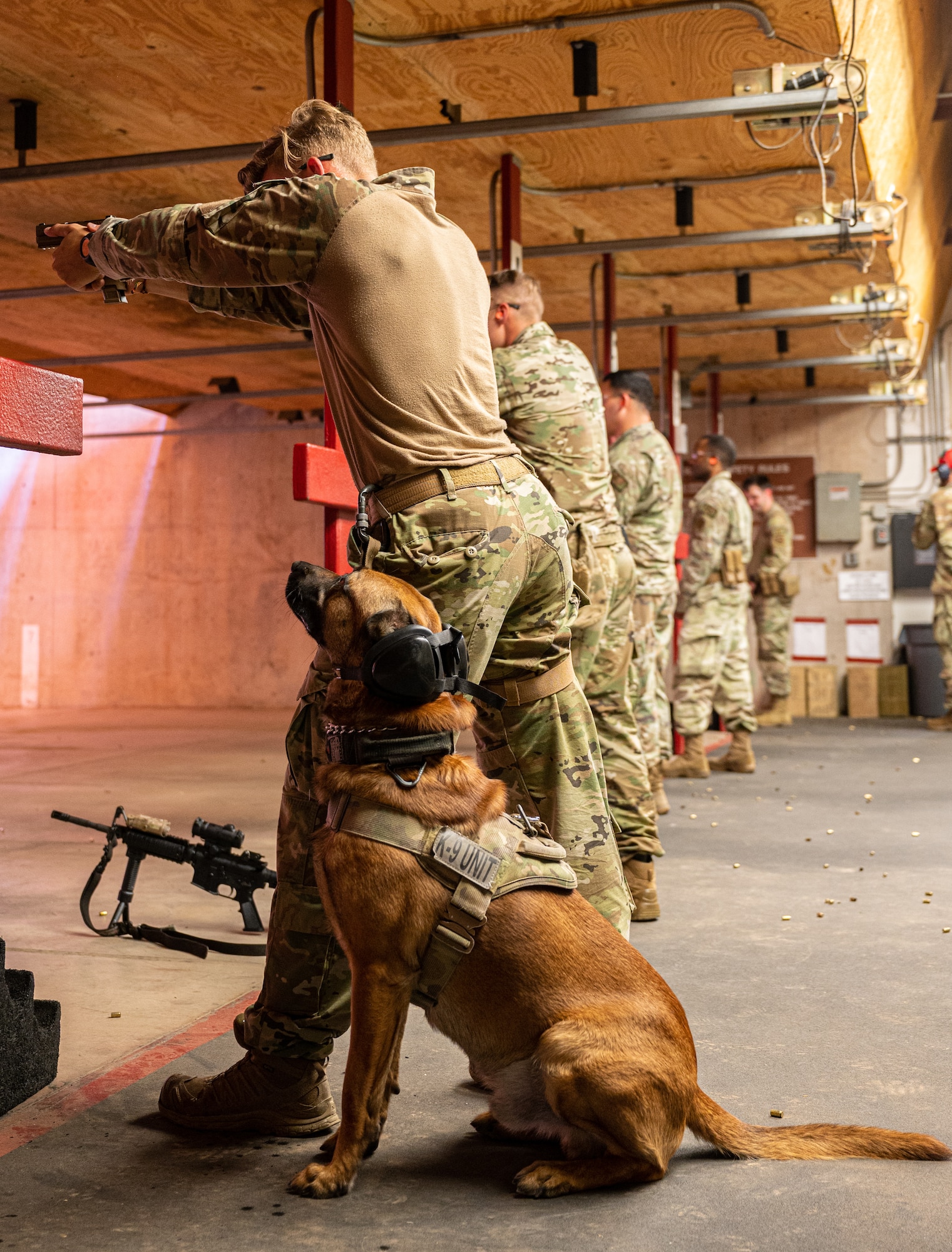 U.S. Air Force Senior Airman Noah Huff, 56th Security Forces Squadron military working dog handler, fires a weapon next to MWD Enzo, during a weapons qualification course Aug. 3, 2021, at Luke Air Force Base, Arizona.