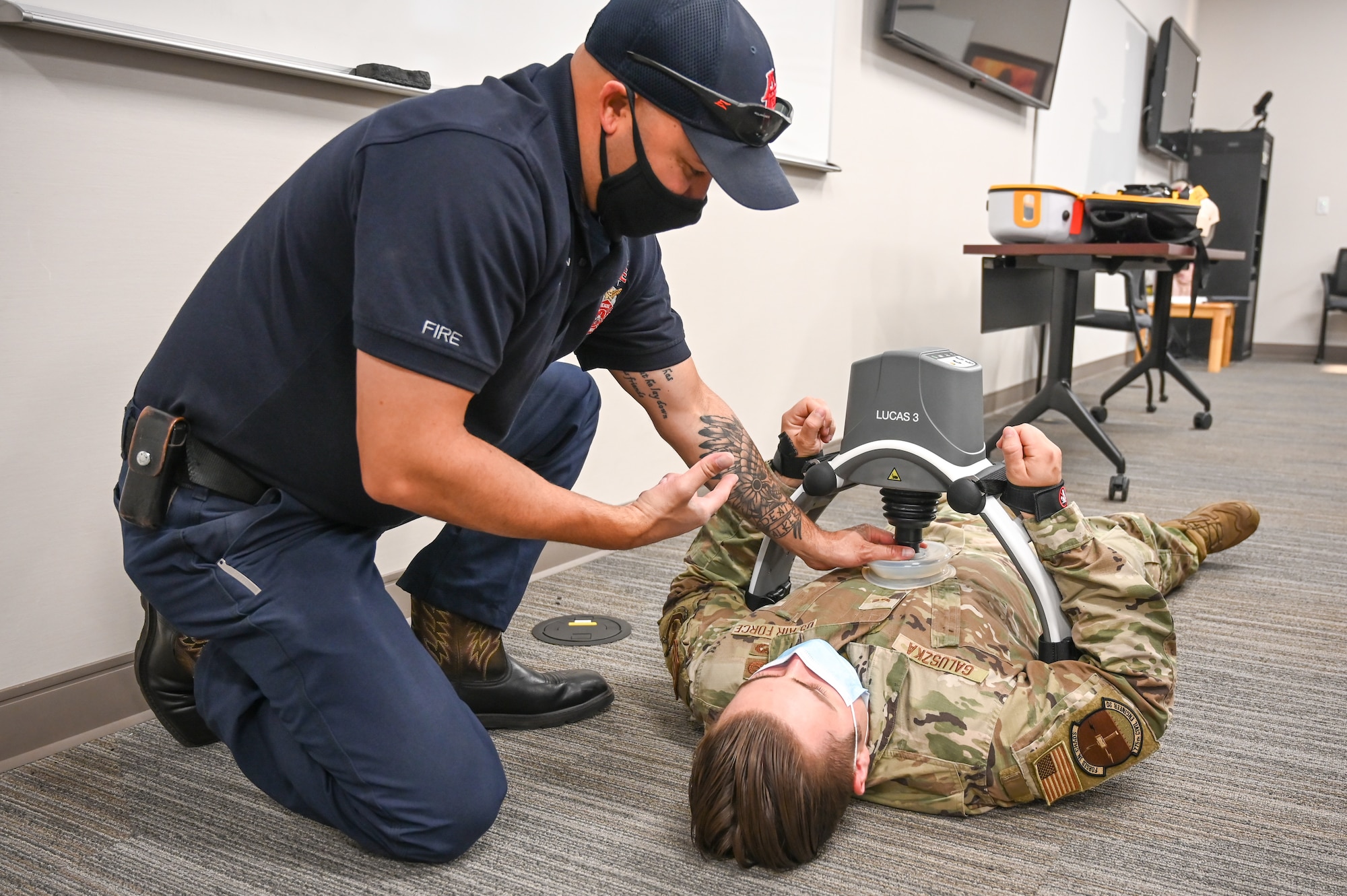 Firefighter Joe Bushman, 775th Civil Engineering Squadron, demonstrates how the LUCAS (Lund University Cardiac Assist System) chest compression system fits with Airman 1st Class Bill Galuszka, 775th CES, Aug. 9, 2021, at Hill Air Force Base, Utah. The LUCAS chest compression system is a portable tool designed to assist rescuers by delivering effective, consistent and continuous chest compressions. (U.S. Air Force photo by Cynthia Griggs)