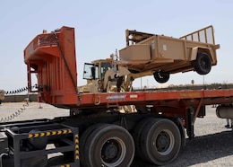 A heavy equipment operator at Camp Arifjan, Kuwait's Lot 54 loads a trailer onto a flatbed for further delivery to Iraqi security forces as part of the Counter ISIS, Train, Equip Fund-I's mission to build military partner capacity. This trailer was the last item out mostly military vehicles, which were in the lot when the Army Reserve Soldiers of the Indianapolis-based 310th Sustainment Command (Expeditionary) who staff the 1st Theater Sustainment Command's operational command post, which included management of the CTEF-I.