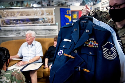 U.S. Air Force Staff Sgt. Kendall Steffen (right), 737th Training Squadron accounting technician, holds up the uniform donated to the Airmen Heritage Museum by retired Senior Master Sgt. Thomas Coons.