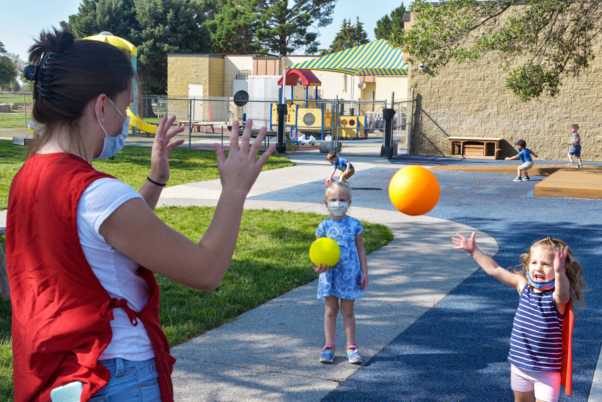 A Child Development Center caregiver throws a ball back and forth with a child during recess on Mountain Home Air Force Base, Idaho.
