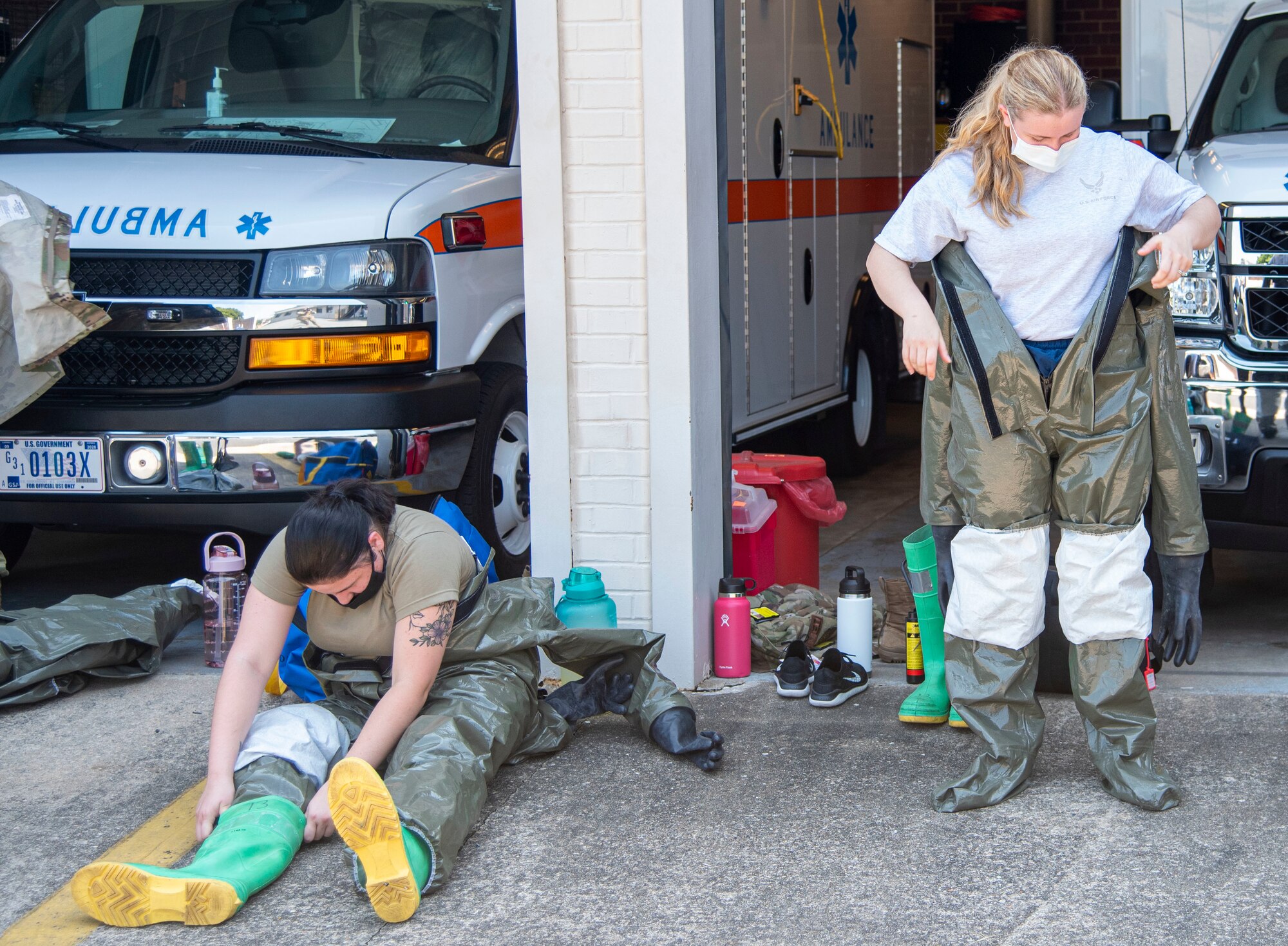 Airman 1st Class Kacie Shaffer, left, 436th Health Care Operations Squadron medical technician, and Airman 1st Class Halli Welch, 436th Operational Medical Readiness Squadron medical technician, don decontamination suits during in-place patient decontamination training at Dover Air Force Base, Delaware, Aug. 11, 2021. The IPPD training helps Airmen practice decontaminating patients affected by chemical, biological, radiological, nuclear or high-yield explosive weapons attacks before entering the clinic for further care. (U.S. Air Force photo by Tech. Sgt. Nicole Leidholm)