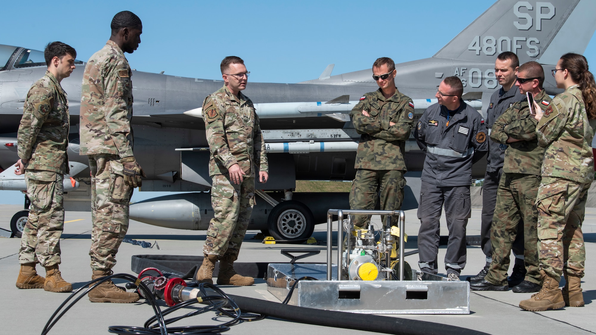 U.S. Air Force Master Sgt. Jason Yunker, 480th Expeditionary Fighter Squadron Fuels Management Flight operations superintendent (center), discusses the Versatile Integrating Partner Equipment Refueling (VIPER) kit, with members of the Polish air force at Łask Air Base, Poland, Aug. 9, 2021. The kit utilizes host nation refueling equipment to support fifth-generation fighters, as well as any U.S. Air Force aircraft anywhere in the world. (U.S. Air Force photo by Tech. Sgt. Anthony Plyler)