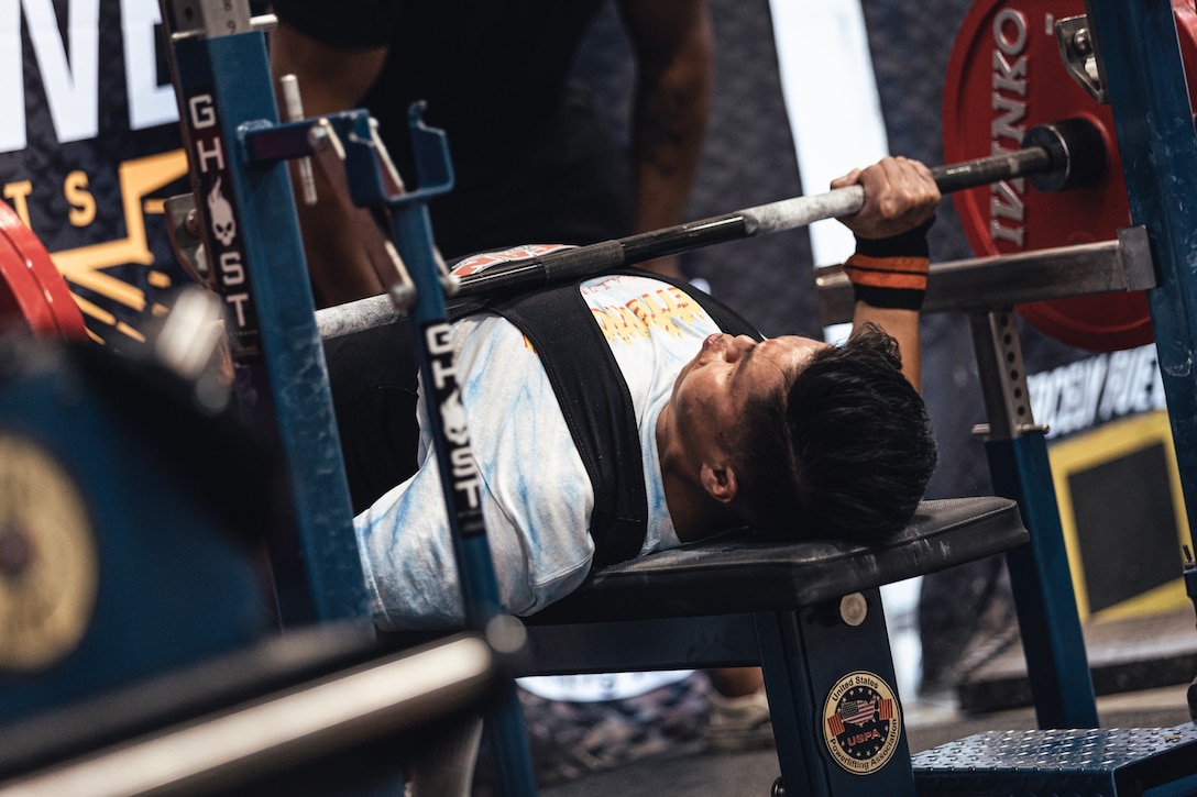 U.S. Marine Corps Cpl. Sean Nguyen completes a maximum repetition on bench press.