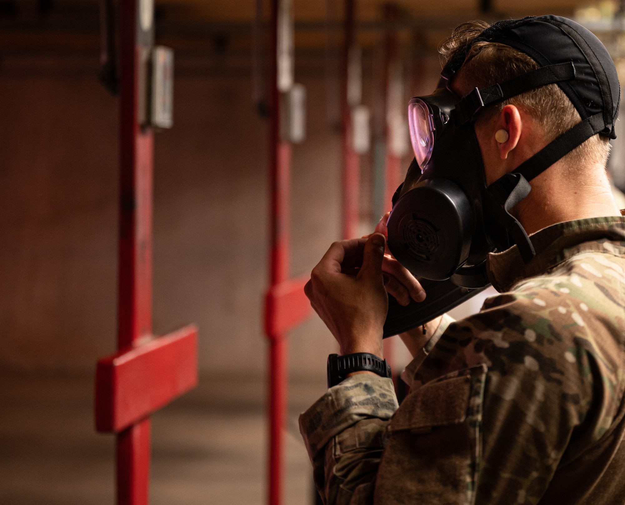 U.S. Air Force Senior Airman Noah Huff, 56th Security Forces Squadron military working dog handler, adjusts his gas mask during a weapons qualification course Aug. 3, 2021, at Luke Air Force Base, Arizona.