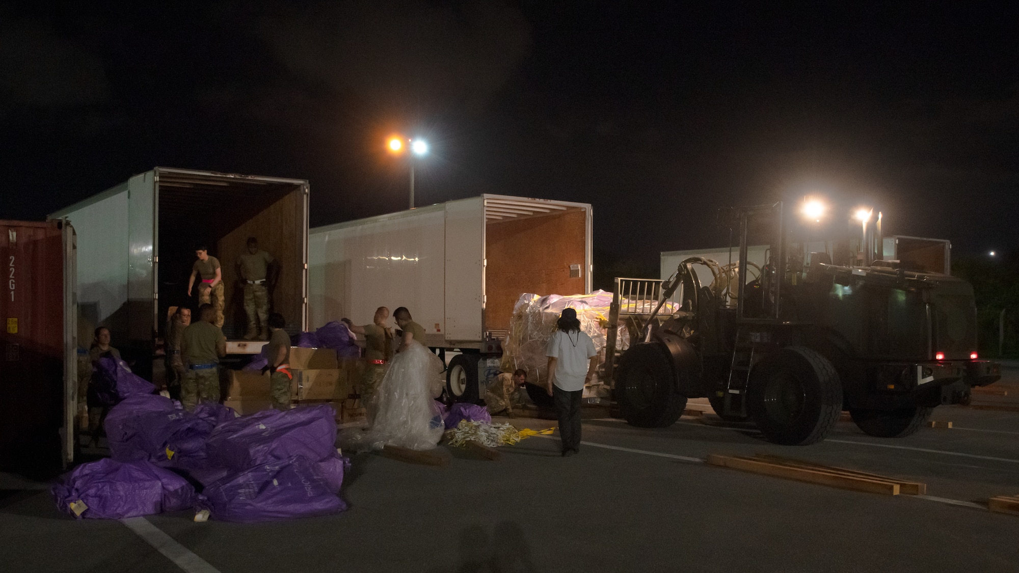 Airmen from the Pacific Air Forces Air Postal Squadron Detachment 3, load packages onto trailers at Kadena Air Base, Japan, July 31, 2021. Airmen from Detachment 3, the 733rd Air Mobility Squadron, 18th Logistics Readiness Squadron, and Camp Kinser Marines delivered over 53 thousand kilograms of mail on this shipment. (U.S. Air Force photo by Airman 1st Class Stephen Pulter)